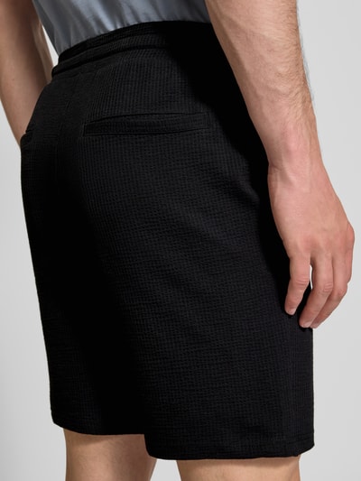 Männermodel trägt Loose Fit Sweatshorts aus Bio-Baumwoll-Mix Modell 'KIAN' von Only & Sons, Optik: Unifarben, Materialverarbeitung: Piqué, Rückansicht Detailaufnahme.