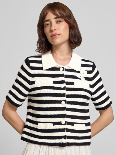 Frauenmodel trägt Strickjacke mit floraler Applikation und 1/2-Arm von Oui, schwarz-weiß gestreift, reine Baumwolle, Nahaufnahme Oberkörper. Regular Fit, Umlegekragen, Knopfleiste, Allover-Look, Rückenlänge 48 cm, Ärmellänge 27 cm.