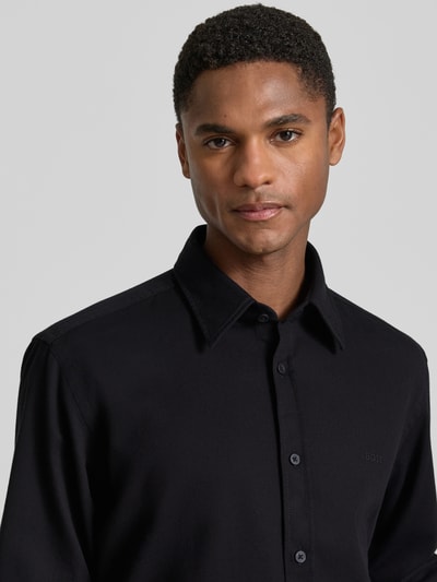 Männermodel trägt Regular Fit vrijetijdsoverhemd uit katoenmix model 'RELEGANT_2_M' van BOSS Orange, look: effen, kentkraag, doorlopende knoopsluiting, labelstitching, labelpatch, achterpas, lange mouwen met manchet, materiaalverwerking: piqué, Nahaufnahme Oberkörper.