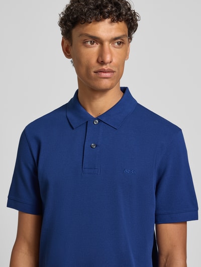 Männermodel trägt Regular Fit Poloshirt aus reiner Baumwolle Modell 'PALLAS' von BOSS in Unifarbe, Nahaufnahme Oberkörper.
