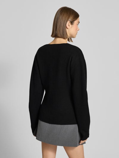 Frauenmodel trägt Regular Fit Strickjacke aus Viskose-Mix in Strick-Optik von Gina Tricot, schwarze Farbe, elastische Ärmelabschlüsse, Rückenlänge 59 cm, Ärmellänge 60 cm, Damen, Ganzkörperansicht Rückansicht.