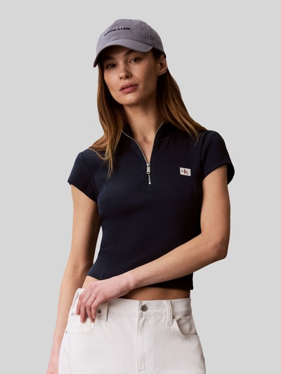 Frauenmodel trägt Slim Fit cropped T-Shirt aus Baumwoll-Mix von Calvin Klein Jeans in Dunkelblau mit kurzem Reißverschluss, Damen T-Shirt, Nahaufnahme Oberkörper.