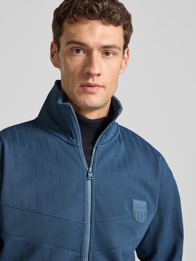 Männermodel trägt Regular Fit Sweatjacke aus Baumwoll-Mix Modell 'DAVRONTO' von HUGO, Farbe Blau, gestreift, Nahaufnahme Oberkörper.