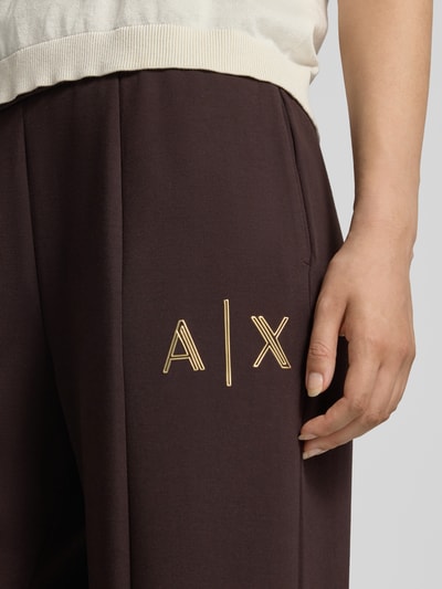 Vrouwenmodel draagt Straight Fit Sweatpants uit elastische viscosemix van Armani Exchange, donkerbruin met labeldetail, binnenbeenlengte maat S 77 cm, detailopname bovenbeen.