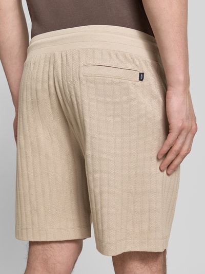 Männermodel trägt Regular Fit Shorts mit Tunnelzug Modell 'JUANITO' von JOOP! Collection, beige, strukturierte Baumwolle, Ganzkörperansicht Rückansicht.