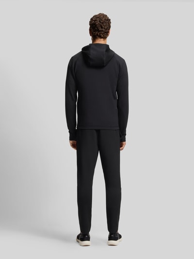 Männermodel trägt schwarze Regular Fit Trainingsjacke aus schnell trocknendem Gewebe Modell 'SICON ACTIVE' von BOSS Green, Ganzkörperansicht Rückansicht.