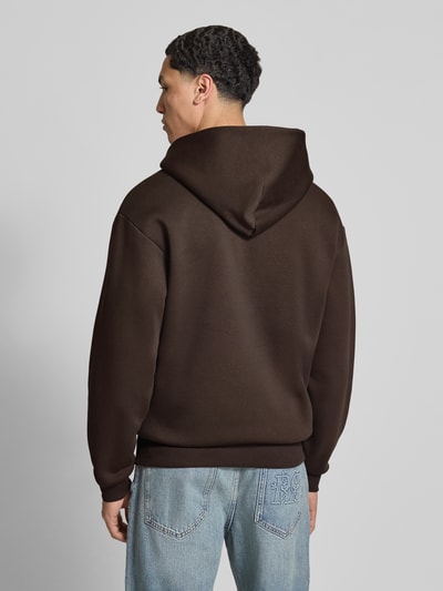 Männermodel trägt Sweatjacke mit Känguru-Tasche von REVIEW in Braun, Baumwoll-Mix, Relaxed-Fit, Rückenlänge 68 cm, Ganzkörperansicht Rückansicht.