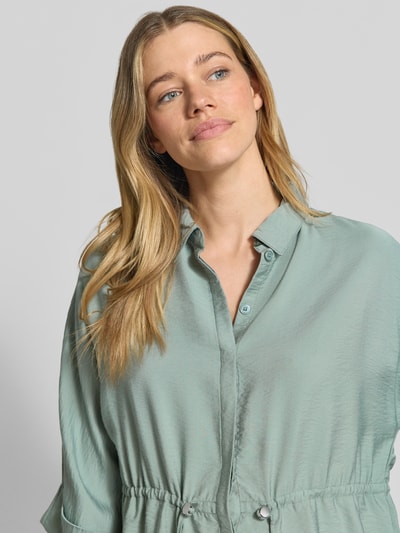 Modelka nosi Relaxed Fit Bluse aus Viskose-Mix mit Umlegekragen od Betty Barclay, pastelowa zieleń, tunel w talii, 3/4 rękaw, widok na górną część ciała z przodu.