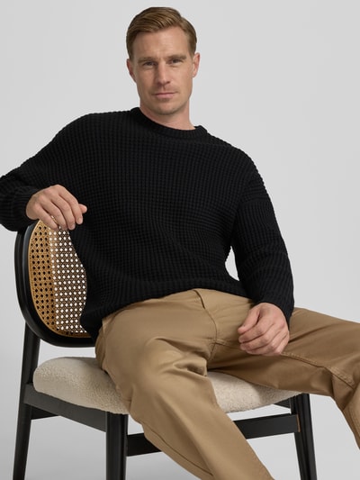 Männermodel trägt schwarzen Strickpullover mit Strukturmuster Modell 'Neelio' von Drykorn, Baumwoll-Mix, Regular-Fit, Nahaufnahme Oberkörper.