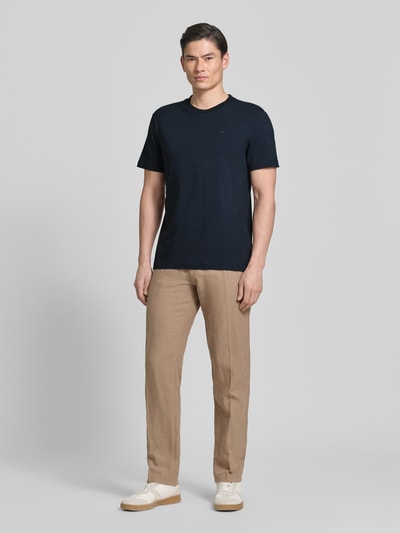 Męski model nosi T-Shirt z okrągłym dekoltem model 'Carlonito' od JOOP! Collection, bawełniany miks ze stretchem, krój straight fit, detal z logo, długość tyłu w rozmiarze M: 71 cm, kolor granatowy, widok całej sylwetki z przodu.