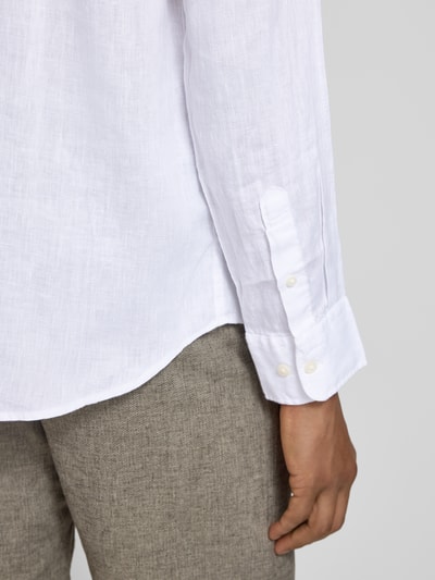 Männermodel trägt Regular Fit Freizeithemd aus reinem Leinen Modell 'REGKYLIAN' von SELECTED HOMME in Weiß, Nahaufnahme Unterkörper. Unifarbene Optik, Flammgarn-Struktur, Sportmanschette mit Knöpfen.