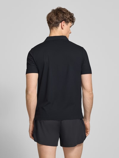 Männermodel trägt schwarzes Slim Fit Poloshirt mit Logo Modell 'EDMOND' von Ellesse, Material-Mix mit Stretch-Anteil, Rückenlänge 63 cm, Ganzkörperansicht Rückansicht.