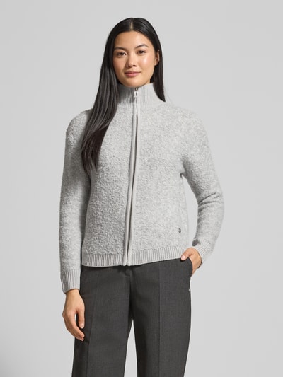 Frauenmodel trägt Strickjacke mit Stehkragen Modell 'Jo44sy' von ZABAIONE im Material-Mix mit Woll-Anteil, Regular Fit, Reißverschluss, in hellem Grau mit feiner, strukturierter Oberfläche, dazu dunkelgraue Hose; Ganzkörperansicht von vorne.