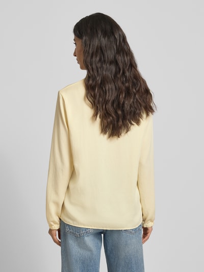 Vrouwenmodel draagt Regular Fit Bluse mit V-Ausschnitt van Marc Cain in lichtgeel met label-detail, lange mouwen, ruglengte 64 cm, Ganzkörperansicht Rückansicht.