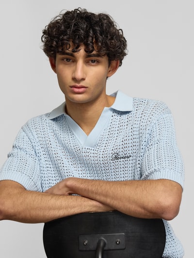 Männermodel trägt Slim Fit Poloshirt in Crochet-Optik von REVIEW in Hellblau aus Reine Baumwolle, Logo-Stitching, Nahaufnahme Oberkörper.