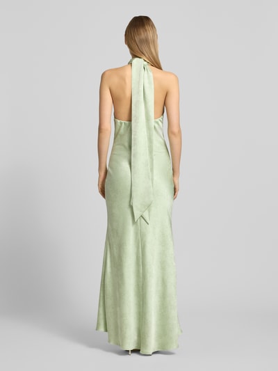 Frauenmodel trägt Abendkleid mit Neckholder und Schluppe Modell 'Fiona' von Neo Noir aus grünem Satin, Körpernaher-Schnitt, Maxikleid, Rückseite, Rücklänge 131 cm, Brustweite 32 cm, Ganzkörperansicht Rückansicht.