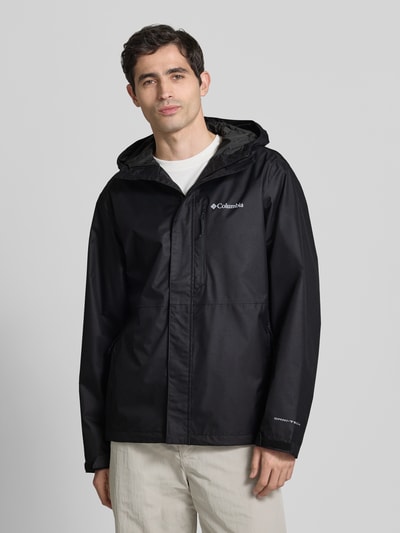 Męski model nosi Kurtkę z kapturem model 'Hikebound™ II' od Columbia, krój regular fit, kolor czarny, patki przy mankietach, logo, zamek błyskawiczny zakryty, długość tyłu w rozmiarze M: 74 cm, szerokość ramion w rozmiarze M: 49 cm, szerokość klatki piersiowej w rozmiarze M: 61 cm, długość rękawów w rozmiarze M: 70 cm, widok całej sylwetki z przodu.