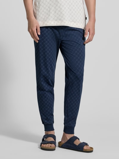 Männermodel trägt Sweatpants mit Logo-Muster und elastischem Bund von JOOP! Collection, Reine Baumwolle, Regular-Fit, Ganzkörperansicht von vorne.