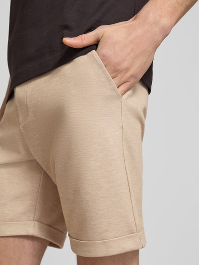 Männermodel trägt Shorts mit elastischem Bund und Gesäßtasche von MCNEAL in Beige, Material-Mix, Nahaufnahme Oberschenkel.