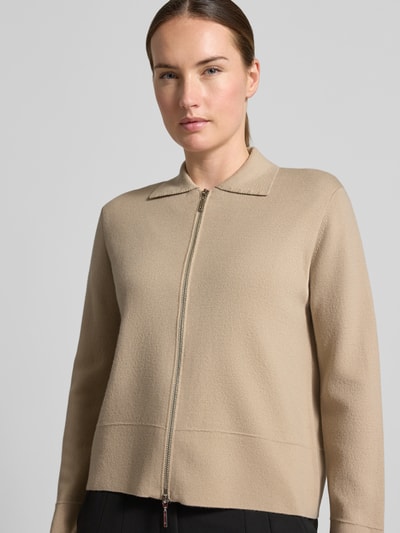 Frauenmodel trägt Strickjacke aus reiner Schurwolle Modell 'SNACK' von MM by Max Mara in Beige, glatte Textur, Nahaufnahme Oberkörper.