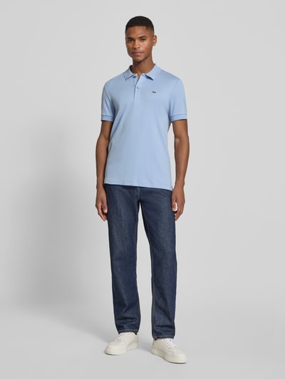 Männermodel trägt Regular Fit Poloshirt aus reiner Baumwolle von Lacoste in Hellblau mit Logo-Detail, unifarben, Ganzkörperansicht von vorne