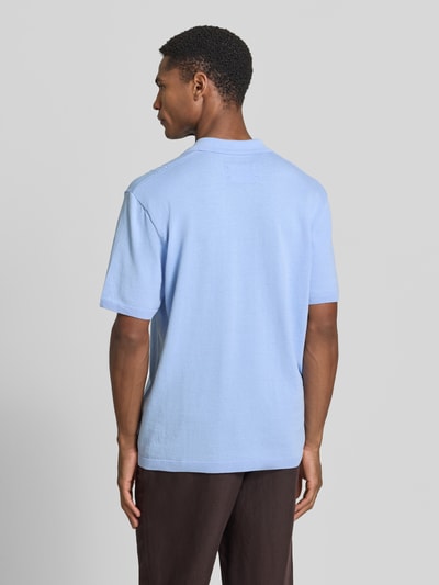 Männermodel trägt Relaxed Fit Poloshirt aus reiner Baumwolle von Armedangels, Optik: Unifarben, Feinstrick, Ganzkörperansicht Rückansicht.