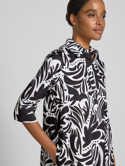 Frauenmodel trägt knielanges Hemdblusenkleid mit verdeckter Knopfleiste von Christian Berg Woman aus Reine Baumwolle mit Straight Fit, Schwarz-Weiß-Muster, Hemdblusenkragen, 1/2-Arm; Brustweite und Rückenlänge bei Größe 36, Nahaufnahme Oberkörper.