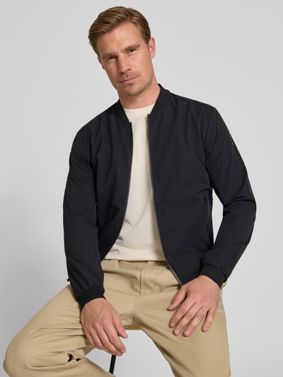 Männermodel trägt Regular Fit Jacke mit Stehkragen Modell 'Campo' von SCANDINAVIAN EDITION in Dunkelblau, Zweiwege-Reißverschluss, Eingrifftaschen, elastische Abschlüsse, Material glatt, Ganzkörperansicht von vorne, Rückenlänge bei Größe M: 67 cm, Schulterbreite: 44 cm, Brustweite: 51 cm, Ärmellänge: 64 cm.