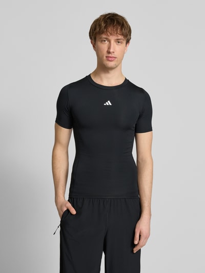 Männermodel trägt schwarzes T-Shirt mit Label-Print von adidas Training, Material-Mix mit Stretch, Slim Fit, Ganzkörperansicht von vorne.