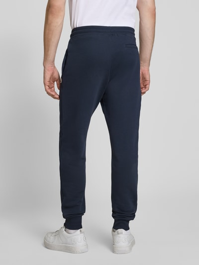 Männermodel trägt Slim Fit Sweatpants aus reiner Baumwolle von Paul Smith in Dunkelblau, elastischer Bund, seitliche und Gesäßtaschen, Ganzkörperansicht Rückansicht.