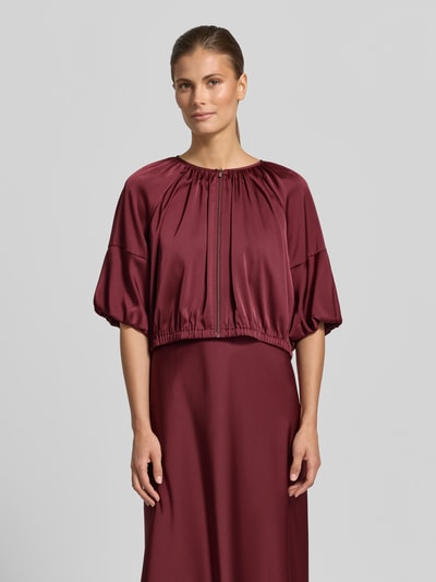 Frauenmodel trägt Cropped Jacke aus Satin mit Reißverschluss von V by Vera Mont in Bordeaux, Rundhalsausschnitt, Rückenlänge 45 cm, Ganzkörperansicht von vorne.