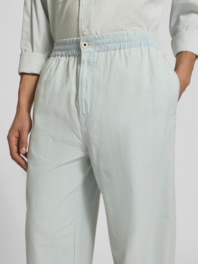 Männermodel trägt Relaxed Fit Sweatpants in Denim-Optik von Kenzo aus reiner Baumwolle mit elastischem Bund, Knopf- und Reißverschluss, Nahaufnahme Oberkörper.