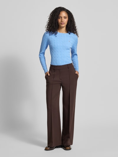 Vrouwenmodel draagt gebreide pullover met kabelpatroon en labelstitching van Gant, katoenmix met stretch, slim fit, ronde hals, ruglengte maat S 58 cm, mouwlengte maat S 61 cm, lichtblauw, egale textuur, voorkant, geheellichaamsaanzicht van voren