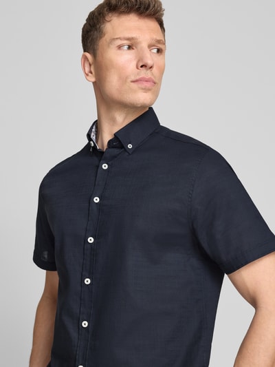 Männermodel trägt Regular Fit Freizeithemd mit Button-Down-Kragen von bugatti in Dunkelblau, Reine Baumwolle, Nahaufnahme Oberkörper. Knopfleiste, Rückenlänge bei Größe M 76 cm, Schulterbreite 46 cm, Ärmellänge 24 cm.