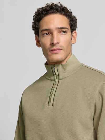 Männermodel trägt Regular Fit Troyer aus reiner Baumwolle Modell 'Sidney' von BOSS in Olivgrün, feine Struktur, Nahaufnahme Oberkörper, Herren Pullover von BOSS.