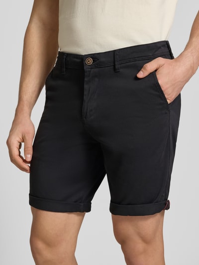 Mannelijk model draagt Regular Fit Shorts met steekzakken model 'BOWIE' van Jack & Jones, mix van katoen en elastaan, regular fit, omslag, bandwijdte maat M 43 cm, binnenbeenlengte maat M 26 cm, zwarte kleur, effen structuur, nahaufnahme bovenlichaam.
