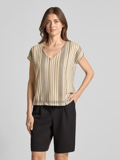 Kobiece modelka nosi damski t-shirt Regular Fit T-Shirt mit Lochstrickmuster Modell 'DEMI' von Vero Moda, beżowe i czarne paski, ażurowy wzór, dekolt w serek, krótki rękaw, dzianina, efekt: wzór na całej powierzchni, krój regular fit, wykończenie materiału: dzianina, Ganzkörperansicht von vorne.