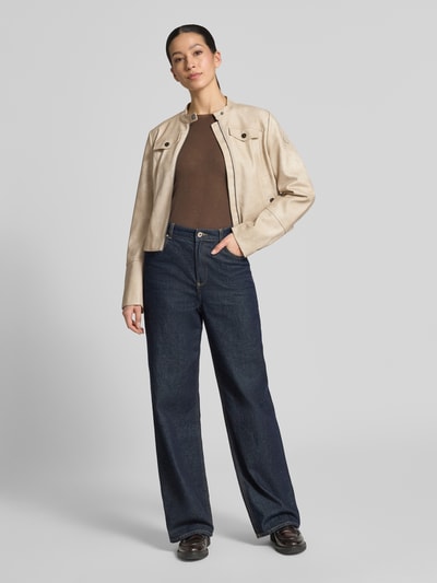 Modelka nosi Slim Fit Jacke in Leder-Optik od Amber & June, materiał skóropodobny, krój slim fit, stójka, brustasza, wpuszczane kieszenie, zamek błyskawiczny dwustronny, długość tyłu w rozmiarze 36: 53 cm, szerokość ramion w rozmiarze 36: 41 cm, szerokość klatki piersiowej w rozmiarze 36: 48 cm, długość rękawów w rozmiarze 36: 65 cm; jasny beż, delikatna faktura, prosty fason, całość na tle szarym, całkowity widok z przodu.