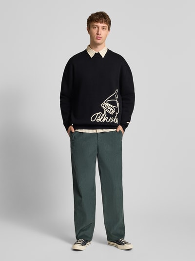 Männermodel trägt schwarzen Strickpullover mit Label-Detail von BLKVIS, Reine Baumwolle, Lockerer Schnitt, Ganzkörperansicht von vorne.
