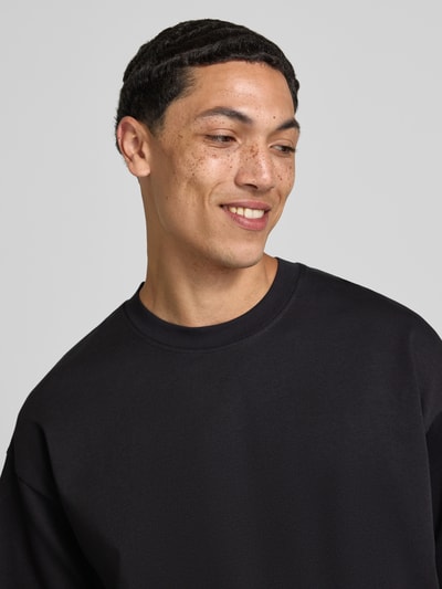 Männermodel trägt Herren T-Shirt mit Rundhalsausschnitt Modell 'BARRON' von Jack & Jones, schwarzer Baumwoll-Mix mit Stretch-Anteil, Relaxed-Fit, Nahaufnahme Oberkörper. Rückenlänge bei Größe M: 73 cm.