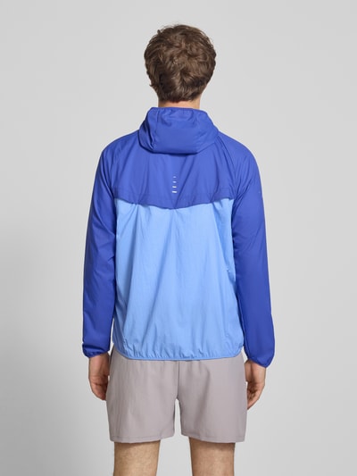 Männermodel trägt Trainingsjacke mit Logo-Print und Kapuze von NIKE TRAINING in Blau, Reißverschluss, glatte Struktur, Ganzkörperansicht Rückansicht.