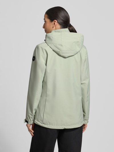 Frauenmodel trägt Parka mit Kapuze und verdecktem Reißverschluss von G.I.G.A. DX in hellem Grün, glatte Textur, Rückenansicht, Ganzkörperansicht. Wassersäule 10.000mm, Kordelstopper, seitliche Reißverschlusstaschen, Label-Patch, Maße bei Größe 36: Rückenlänge 70 cm, Schulterbreite 41 cm, Brustweite 51 cm, Ärmellänge 63 cm.
