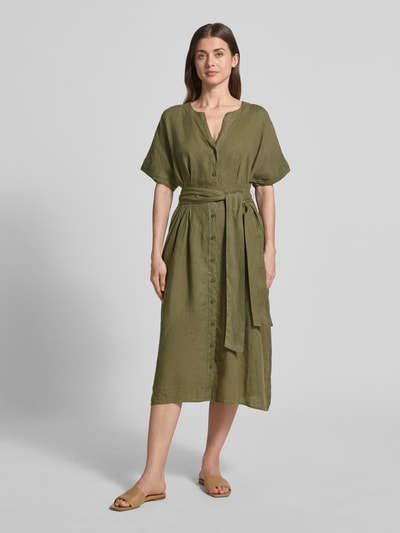 Frauenmodel trägt Midikleid aus reinen Leinen mit Tunika-Ausschnitt Modell 'Soli' von Christian Berg Woman Selection in Olivgrün, Knopfleiste, Stoffband, taillierte Passform, kurzärmelig, Ganzkörperansicht von vorne.