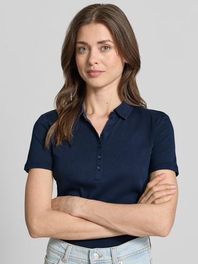 Modelka kobieca nosi Regular Fit Poloshirt aus reiner Baumwolle od Tom Tailor, granatowy jersey, krótki rękaw, polokołnierzyk, widok na górną część ciała z przodu.