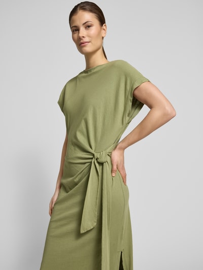 Frauenmodel trägt Midikleid aus reiner Baumwolle von Scotch & Soda in Hellgrün mit Knoten-Detail, taillierte Passform, Nahaufnahme Oberkörper.