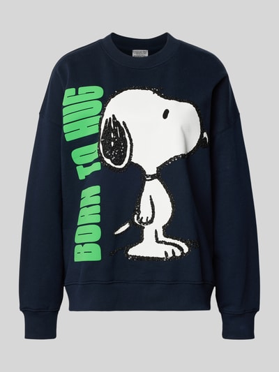 Frauenmodel trägt Loose Fit Sweatshirt aus reiner Baumwolle Modell 'JUMBRELLA EMBO' von Essentiel Antwerp mit Optik: Unifarben, Motiv-Print, Pailletten und Perlen, überschnittenen Schultern, Rundhals, Langarm, gerippten Abschlüssen und Materialverarbeitung: Sweat, Farbe Dunkelblau mit grünem Schriftzug, Ganzkörperansicht von vorne.