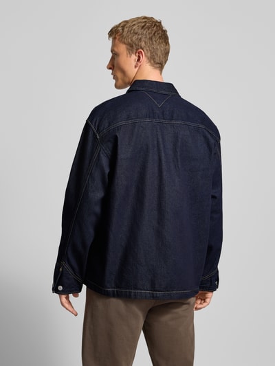 Männermodel trägt Regular Fit Jeansjacke aus reiner Baumwolle von Tommy Jeans in Melange-Optik, Denimstruktur, Ganzkörperansicht Rückansicht.
