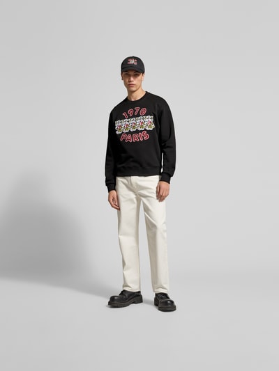 Männermodel trägt Sweatshirt aus reiner Baumwolle von Kenzo in Schwarz mit Label-Print, lockerer Passform, Rundhalsausschnitt, elastischen Abschlüssen, Rückenlänge 66 cm bei Größe M, Ganzkörperansicht von vorne.