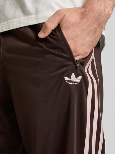 Mannenmodel draagt Sweatpants met elastische tailleband van adidas Originals, losvallende pasvorm, label-stitching, zijritszakken, detailopname bovenbeen.
