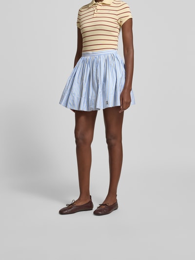 Frauenmodel trägt Minirock aus reiner Baumwolle von Rabanne in A-Linie mit Ziernähte, Label-Detail, blauer Streifen, Minilänge, Nahaufnahme Unterkörper von vorne.